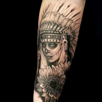 Tattoo of a native american headdress with full skull paint and a sunflower done in black and grey.